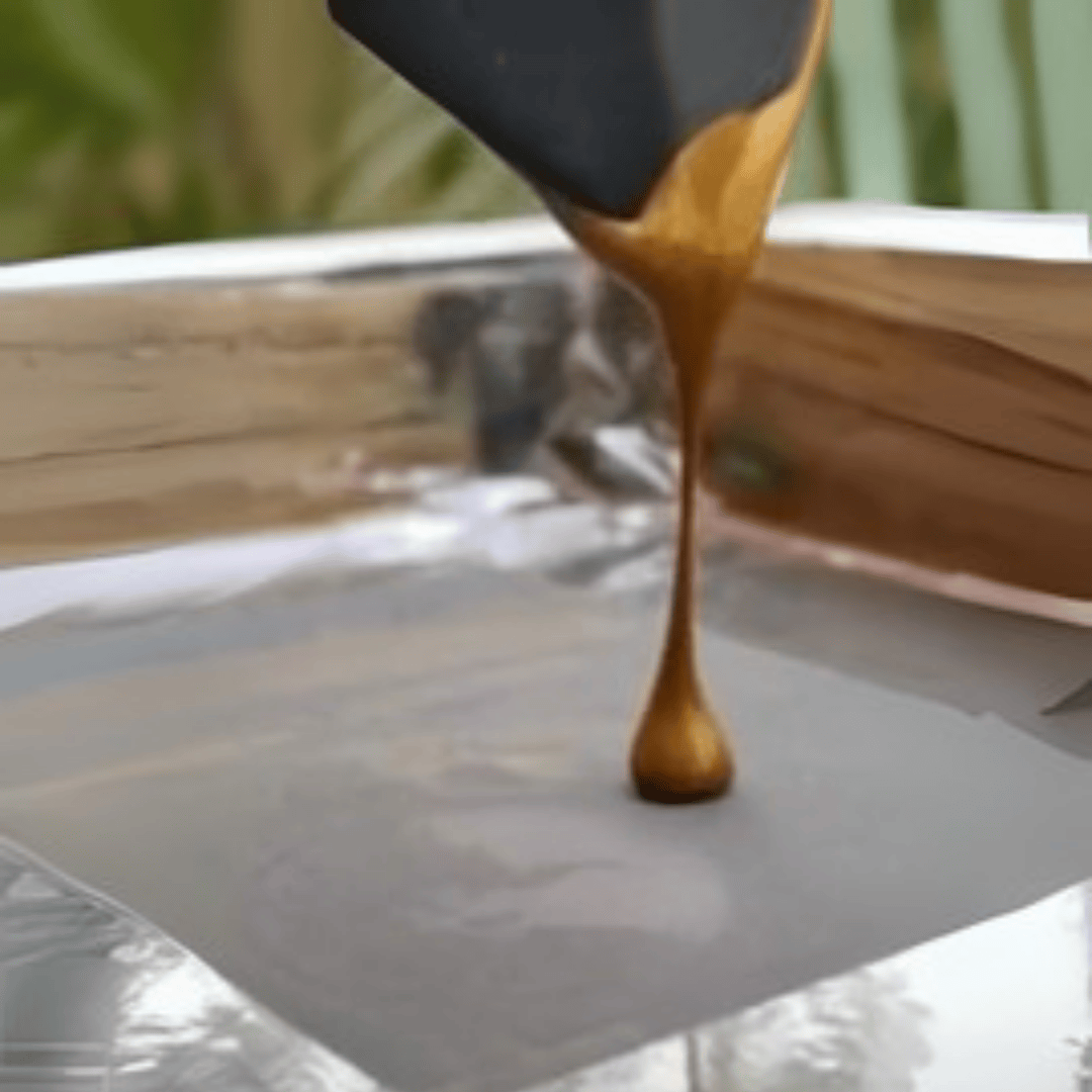 Wooden spatula drizzling brown liquid onto a white surface with a blurred background