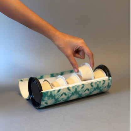 Hand holding a cylindrical container with rolls of paper against a neutral background